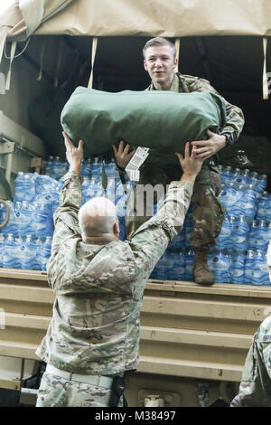 Ohio National Guard Soldaten der 285. Medical Unternehmen (Bereich Support) Last Wasser und Mission erforderliche Ausrüstung auf eine Light Medium Tactical Vehicle (LMTV) Oktober 3, 2017, in Vorbereitung auf die Bewegung zu Puerto Rico von Rickenbacker Air National Guard Base in Columbus, Ohio. Die Ohio National Guard und andere militärische Kräfte arbeiten gemeinsam daran, die zur Unterstützung der zivilen Behörden Hilfe und Erleichterung für die Betroffenen durch den Hurrikan Maria zur Verfügung zu stellen. (Ohio National Guard Foto von Sgt. Joanna Bradshaw) Betrieb Scarlet Hurrikan Advance Party durch Ohio National Guard Stockfoto