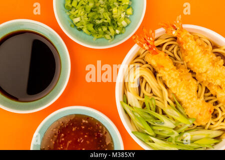 Im japanischen Stil Tiger Garnelen Tempura Nudelsuppe mit Frühlingszwiebeln gegen einen orangen Hintergrund Stockfoto