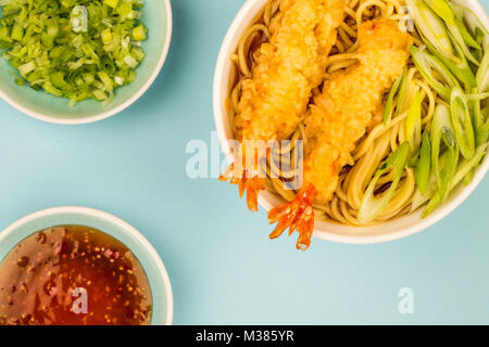 Im japanischen Stil Tiger Garnelen Tempura Nudelsuppe mit Frühlingszwiebeln gegen einen hellblauen Hintergrund Stockfoto