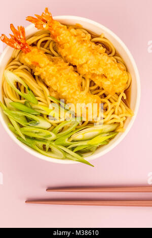 Im japanischen Stil Tiger Garnelen Tempura Nudelsuppe mit Frühlingszwiebeln gegen eine blass rosa Hintergrund Stockfoto