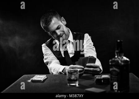 Harter Kerl spielen seine Karten in der Nähe von seiner Brust am Pokertisch Stockfoto