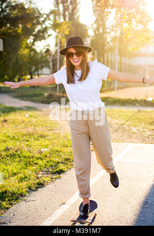 Weibliche reiten ein Skateboard bei Sonnenuntergang. Stadt urban Lifestyle Stockfoto