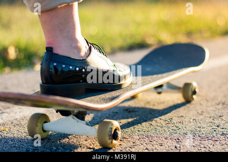 Weibliche reiten ein Skateboard bei Sonnenuntergang. Stadt urban Lifestyle Stockfoto