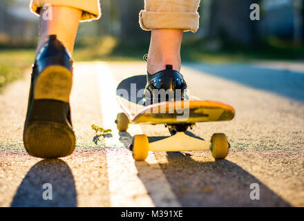 Weibliche reiten ein Skateboard bei Sonnenuntergang. Stadt urban Lifestyle Stockfoto