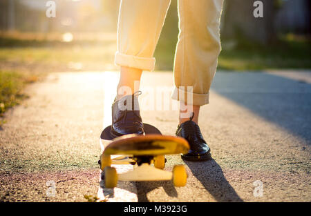 Weibliche reiten ein Skateboard bei Sonnenuntergang. Stadt urban Lifestyle Stockfoto