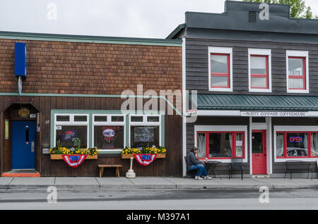 Vom 6. Juli 2017 - Haines, Alaska, USA; amerikanische Kleinstadt kulturellen Momentaufnahme der sitzenden Person außerhalb Coffee Shop neben der Bar. Stockfoto