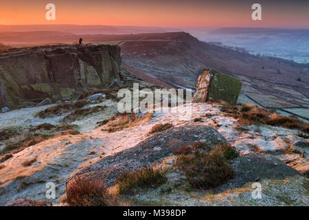 Ein Fotograf steht in der Dämmerung Frost bedeckt Curbar Kante im Winter, in der Nähe von Calver, Nationalpark Peak District, Derbyshire, England, Großbritannien Stockfoto