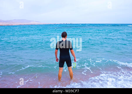 Junger Mann in Anzug geht auf das Meer im Sommer im Freien Stockfoto