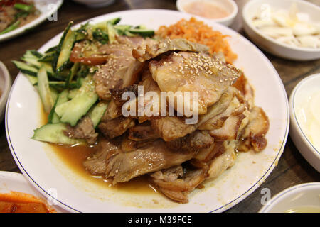 Koreanischen Stil geschmorten Schweinebauch mit Beilagen Gurken und essbare Quallen im Koreanischen Restaurant, Südkorea Stockfoto