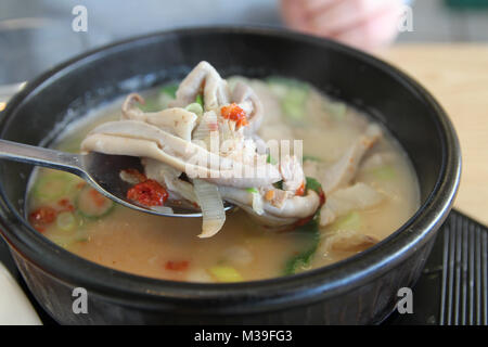 Koreanische Schweinefleisch Reissuppe (Dwaeji - gukbap) mit dem Fokus auf Schweine Bauch in eine dampfende Schüssel am Stein koreanisches Restaurant, Busan, Südkorea Stockfoto