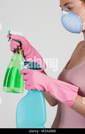 MODEL RELEASED. In der Nähe von Frau mit Gesichtsmaske holding Reinigungsmittel in ihren Handschuhen. Stockfoto