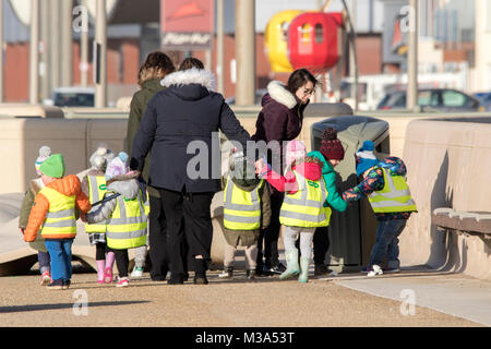 Eine Gruppe von begleitet Schulkinder tragen Hi viz Westen auf einen Ausflug oder Reise, Cleveleys, Lancashire, Großbritannien. Stockfoto