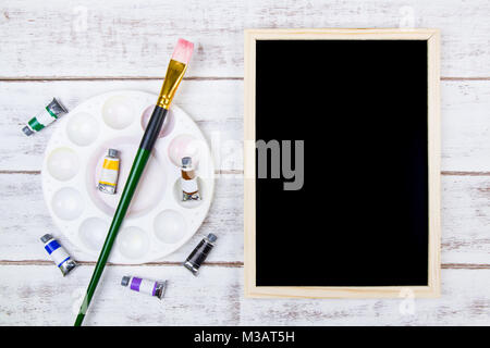 Das Aquarell Palette und Pinsel auf weißem Hintergrund aus Holz mit Blackboard und Kopieren. Vorlage mock up für ihr Design und ihre Kopie sp Stockfoto