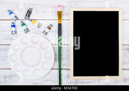 Das Aquarell Palette und Pinsel auf weißem Hintergrund aus Holz mit Blackboard und Kopieren. Vorlage mock up für ihr Design und ihre Kopie sp Stockfoto