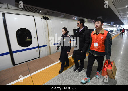 Nanjing in der chinesischen Provinz Jiangsu. 9 Feb, 2018. Chen Deyu (C) nimmt einen Zug an der Nanjing South Railway Station mit Hilfe der ein Verwalter und ein Freiwilliger in Nanjing, der Hauptstadt der ostchinesischen Provinz Jiangsu, Feb 9, 2018. Chen Deyu, einem blinden Masseur Geboren 1988, erhielt Hilfe von der '158' Freiwilligendienst Gruppe der Nanjing South Railway Station von Nanjing in seine Heimatstadt in Anhui. Die Gruppe, im Jahr 1968, ist auf die Unterstützung der abzielen müssen sich auf ihren Reisen. Credit: Li Bo/Xinhua/Alamy leben Nachrichten Stockfoto