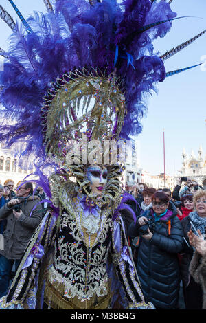 Venedig, Venetien, Italien, 10. Februar 2018. Bunte Kostüme beim Karneval in Venedig an einem sonnigen Tag am letzten Wochenende des Festivals. Person in aufwendigen Maske in Piazza San Marco mit den Massen. Stockfoto