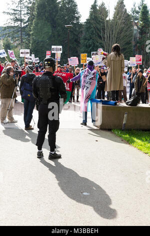 Seattle, Washington, USA. 10. Februar, 2018. Ein Unterstützer spricht als Seattle Bereitschaftspolizei Blick auf die Student-led gegen den Protest der Patriot Gebet Freiheit Sammlung an der Universität von Washington. Die UW International Socialist Organisation und mindestens Dutzend andere UW Vereinen organisiert den Protest, den Schatten der Freiheit Rallye. Durch die japanisch-amerikanischen Aktivist Joey Gibson, der umstrittenen konservativen Gruppe Patriot Gebet spricht sich zugunsten der freien Rede gegründet und wendet sich gegen große Regierung. Credit: Paul Christian Gordon/Alamy leben Nachrichten Stockfoto