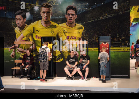 Köln, Deutschland - 24. August 2017: Jungen stehen und sitzen vor einem BVB Werbung für Pro Evolution Soccer aus dem Hause Konami an Gamescome 2 Stockfoto