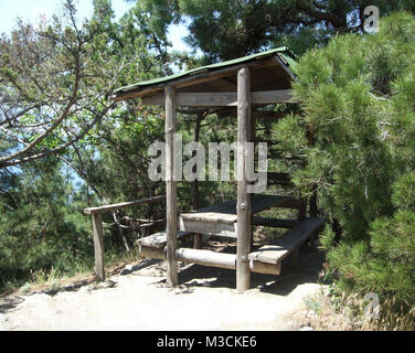 Holz- Tisch und Bank unter einem Baldachin Unter den Tannen im Wald. Stockfoto