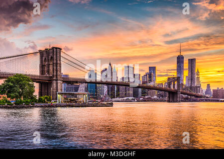 Skyline von New York City auf den East River und die Brooklyn Bridge bei Sonnenuntergang. Stockfoto