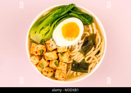 Im japanischen Stil vegetarisch Tofu Nudeln Ramen Suppe oder Brühe gegen eine blass rosa Hintergrund Stockfoto