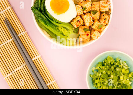 Im japanischen Stil vegetarisch Tofu Nudeln Ramen Suppe oder Brühe gegen eine blass rosa Hintergrund Stockfoto