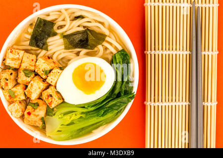 Im japanischen Stil vegetarisch Tofu Nudeln Ramen Suppe oder Brühe auf rotem Hintergrund Stockfoto