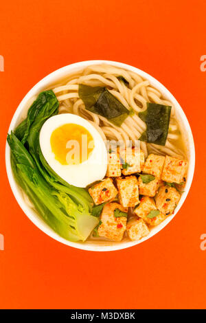 Im japanischen Stil vegetarisch Tofu Nudeln Ramen Suppe oder Brühe auf rotem Hintergrund Stockfoto