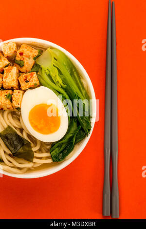 Im japanischen Stil vegetarisch Tofu Nudeln Ramen Suppe oder Brühe auf rotem Hintergrund Stockfoto