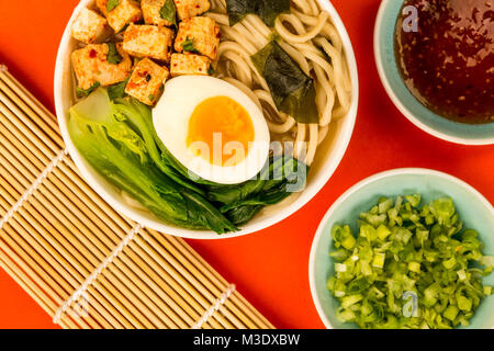 Im japanischen Stil vegetarisch Tofu Nudeln Ramen Suppe oder Brühe auf rotem Hintergrund Stockfoto