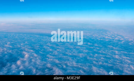 Luftaufnahme von dichten Wolken aus dem Flugzeugfenster mit Licht von Links Stockfoto