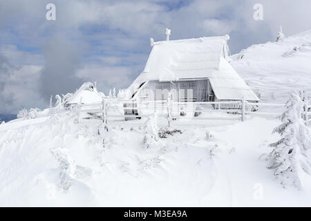 Gefroren und schneebedeckt Holzhütte an einem bewölkten Tag, Velika Planina, Slowenien. Stockfoto