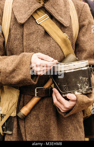 Topf für Lebensmittel in den Händen eines sowjetischen Soldaten, gekleidet in einen Mantel Stockfoto