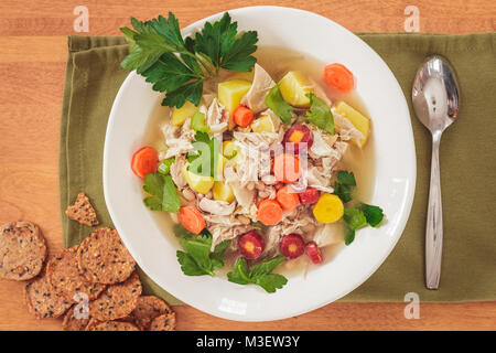 Ansicht von oben mit hausgemachten Huhn und weißen Bohnen Suppe in einer weißen Schüssel. Vollkorn cracker Akzent die Einstellung mit grünen Serviette und Löffel. Stockfoto