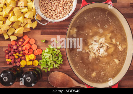 Ansicht des verwendeten Zutaten hausgemachte Huhn und weißen Bohnen Suppe zu machen. Zutaten gehören geschnittene Karotten, Sellerie, Kartoffeln, und weiß b Stockfoto