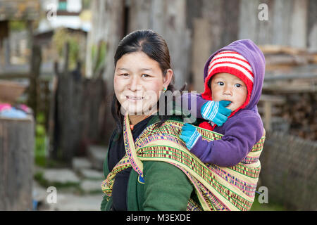 Phobjikha, Bhutan. Frau mit Kind auf dem Rücken, Kikorthang Dorf. Stockfoto