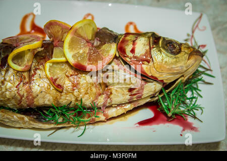 Fisch mit Zitrone Keile und eine grüne Rosmarin. Geringe Tiefenschärfe. Stockfoto