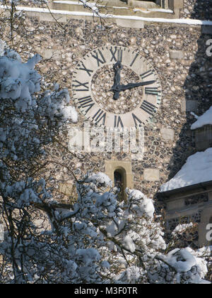St Paul's Kirche in Woldingham Surrey, dem Zifferblatt und den schneebedeckten Bäumen im Vordergrund. Stockfoto