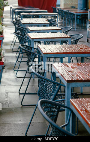 Tische mit Stühlen, ein straßencafe mit Regentropfen fallen nach dem Regen in London Stockfoto