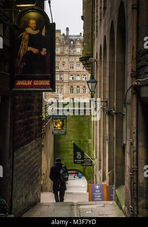 Man Walking in John Knox Gasse mit jinglin Geordie und Halfway House Pub Zeichen, Edinburgh, Schottland, Großbritannien mit Balmoral Hotel in Abstand Stockfoto