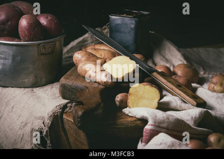 Vielzahl von Roh ungekocht Biokartoffeln unterschiedlicher Art und Farben Rot, Gelb, Lila auf Holz Schneidebrett mit Küche Handtücher über schwarze Tabelle. D Stockfoto