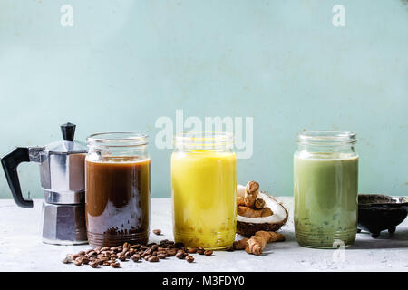 Vielzahl von bunten Iced Latte Getränke. Eiskaffee, Kurkuma und Matcha Latte Cocktails in Gläsern mit Zutaten oben über Grau Grün Textur b Stockfoto