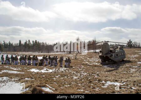 Soldaten Line up bereit, eine CH-47 Chinook Hubschrauber von B-Company, 3-10 Allgemeine Unterstützung Aviation Battalion, 10 Combat Aviation Brigade, 10 Mountain Division Board zu, während eines kalten Last Training über die Angriffe am Fort Drum, New York, am 2. Februar. Die Air Assault Operation dauerte sechs Tage, mit Fliegern Ausbildung und die Ausführung der Bewegung der Luft mit drei Unternehmen der Soldaten aus 2 Battalion, 87th Infantry Regiment, 2nd Brigade Combat Team, 10-Mountain Division (LI). (U.S. Armee Stockfoto