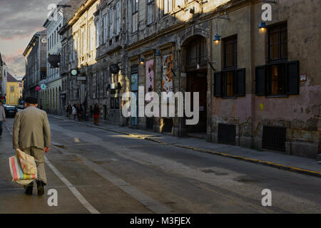 Ältere Mann mit leeren Beutel zu Fuß auf düsteren Akacfa street in Budapest Stockfoto