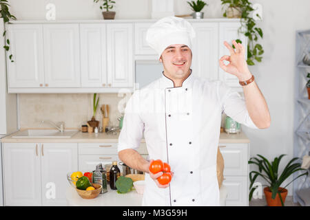 Koch mit Tomaten in der hand Geste ok Stockfoto