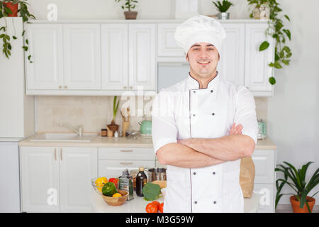 Porträt eines lächelnden männlichen Chefs mit gekochten Speisen stehen in der Küche Stockfoto