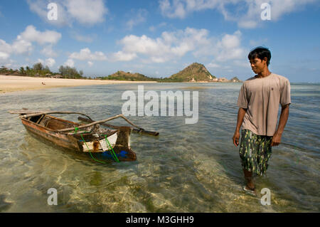 Ein Fischer neben seinem Boot am Strand von Kuta Beach, einem Fischerdorf im Süden von Lombok Indonesien Stockfoto