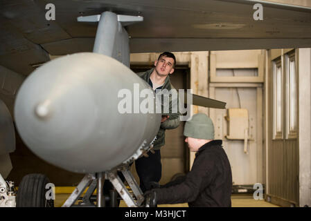 Staff Sgt. Michael Albrecht und Senior Airman Colin Prutch des 52 Aircraft Maintenance Squadron ein Kotflügel befestigen - Kraftstofftank an einen US Air Force F-16 CM Fighting Falcon in Spangdahlem Air Base, Deutschland, Feb 6, 2018 montiert. Ein Schneesturm ein Halt auf den Flugbetrieb für den Tag aber nicht die Notwendigkeit, die für die allgemeine Wartung der Spangdahlem Flotte von F-16 zu stoppen. Flieger zugeordnet zu den 52 AMXS sind mit der Pflege und Instandhaltung der einzige US-Flugzeuge spezialisiert auf die Unterdrückung der gegnerische Luftabwehr (sead) Rolle im europäischen Theater der Operationen betraut. (U.S. Air Force Stockfoto