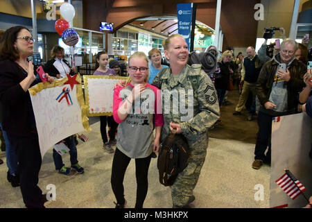 Us Air Force Senior Master Sgt. Susan Schroeder, der die 119 Communications Flug, hält ihre Tochter fest, wie sie von der Familie und von den Freunden nach ihrer Rückkehr nach Hause zu Hector International Airport, Fargo, N.D., Feb 6, 2018 begrüßt wird. Während es sind fast immer auch ein paar Einheit Mitglieder rund um die Welt zu einem bestimmten Zeitpunkt eingesetzt, sie ist das letzte Mitglied der fast 150 Glückliche Hooligans, die als Teil von Air Expeditionary Force Bereitstellung des Geräts Zyklus im Jahr 2017 eingesetzt. (U.S. Air National Guard Stockfoto