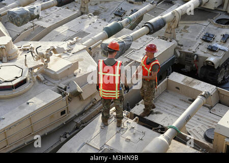 Der SHUAIBA, Kuwait - U.S. Army Staff Sgt. Jonathan Odom Gespräche mit Sgt. Rico Ratley, sowohl der 335 Transport Distanz, zu diskutieren, mit denen die Fahrzeuge während der Übung Bügeleisen Union an Bord der US-Armee Logistik Support Vessel, SP/4 James eine Loux, am Hafen von Shuaiba, Kuwait 08. Januar 2018. (U.S. Armee Stockfoto